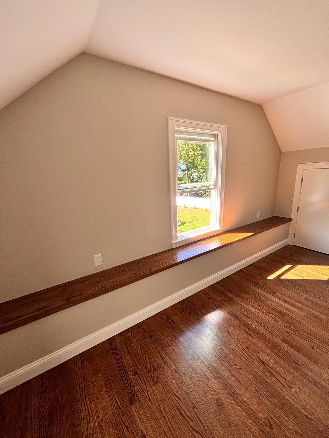 Long stained-oak window ledge with matching baseboard trim